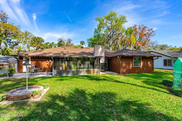 back of house featuring a yard, a chimney, a sunroom, a patio area, and fence