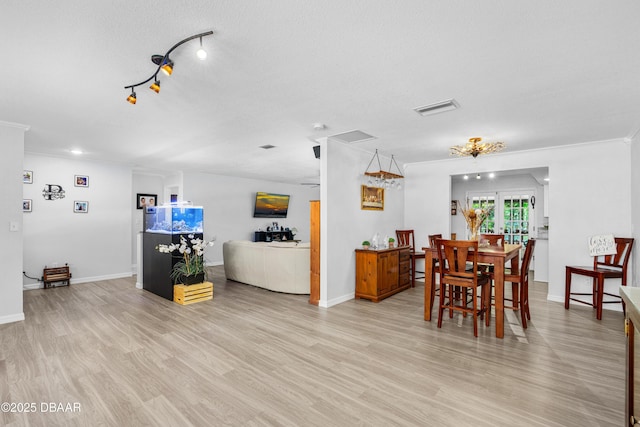 dining space featuring light wood-type flooring, visible vents, crown molding, and baseboards