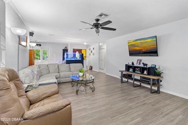 living room with baseboards, crown molding, visible vents, and wood finished floors