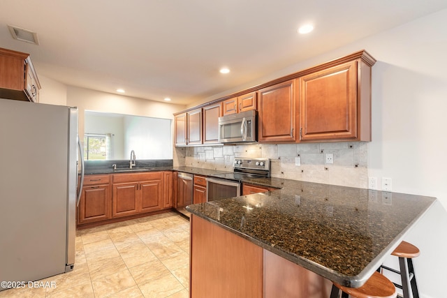 2017 Cornell Pl, Port Orange, FL 32128 - kitchen with stainless steel appliances, a peninsula, backsplash, dark stone counters, and recessed lighting