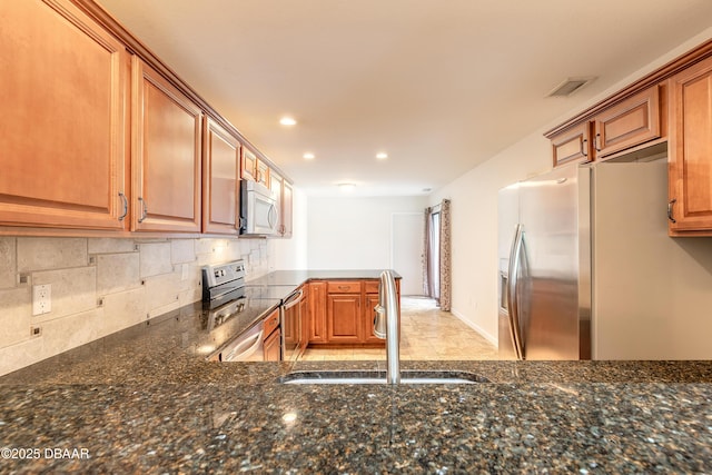 2017 Cornell Pl, Port Orange, FL 32128 - kitchen featuring appliances with stainless steel finishes, backsplash, dark stone countertops, recessed lighting, and brown cabinetry
