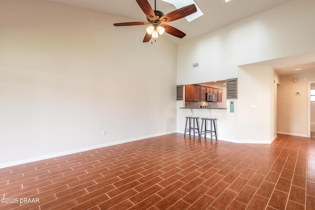 2017 Cornell Pl, Port Orange, FL 32128 - unfurnished living room with high vaulted ceiling, a ceiling fan, dark wood-type flooring, and a skylight