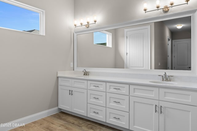 bathroom featuring double vanity, baseboards, a sink, and wood finished floors