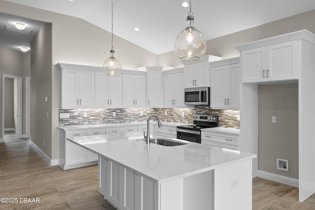 kitchen featuring stainless steel appliances, a sink, white cabinets, light countertops, and light wood-type flooring