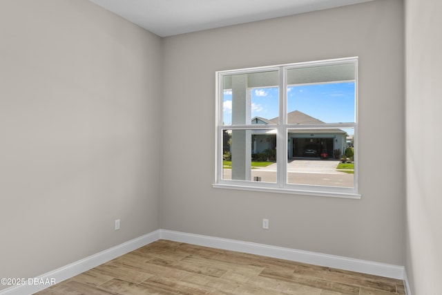 spare room with baseboards and wood finished floors