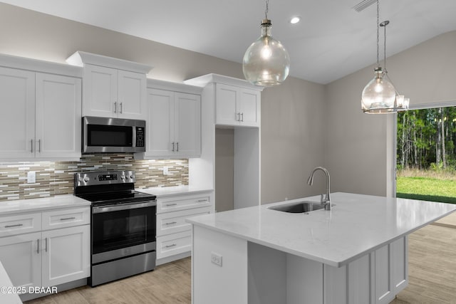 kitchen featuring appliances with stainless steel finishes, white cabinets, a sink, and light wood finished floors