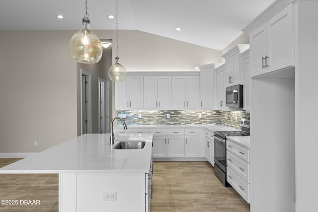 kitchen featuring appliances with stainless steel finishes, vaulted ceiling, light countertops, white cabinetry, and a sink