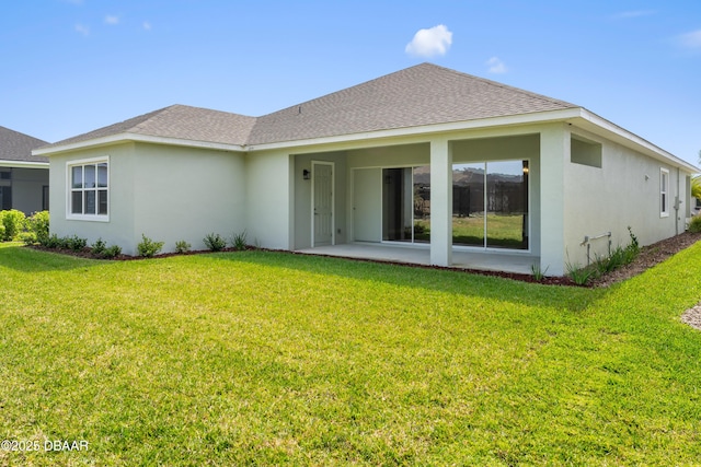 back of property featuring a shingled roof, a lawn, and stucco siding