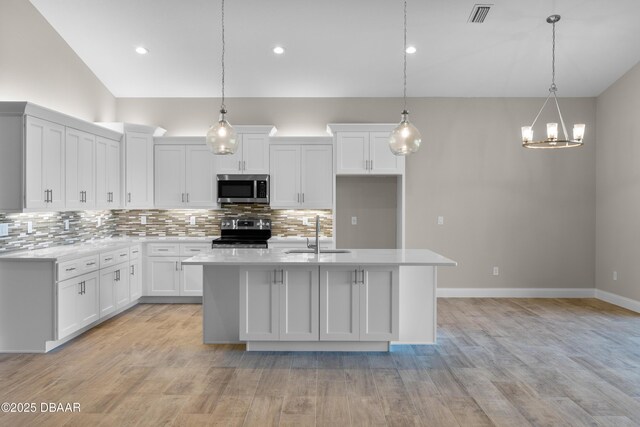 kitchen with appliances with stainless steel finishes, light countertops, visible vents, and a sink