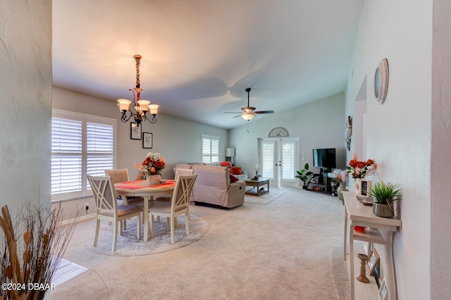 dining room featuring ceiling fan with notable chandelier, light colored carpet, and lofted ceiling