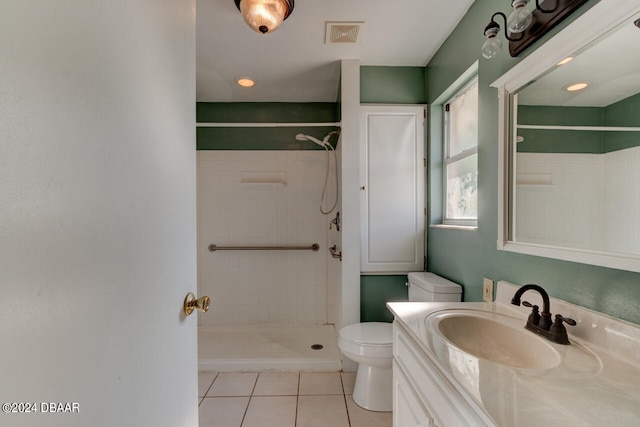 bathroom with vanity, tile patterned flooring, toilet, and tiled shower