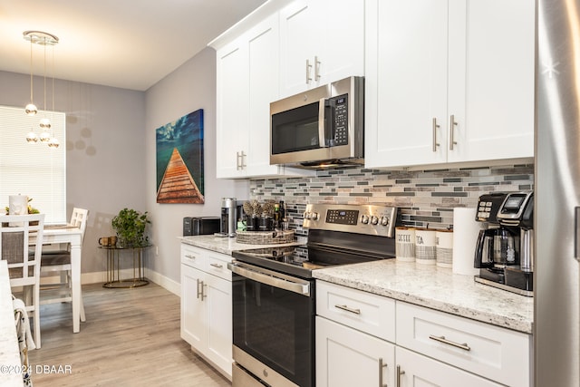 kitchen featuring stainless steel appliances, light stone countertops, white cabinetry, light hardwood / wood-style flooring, and decorative light fixtures