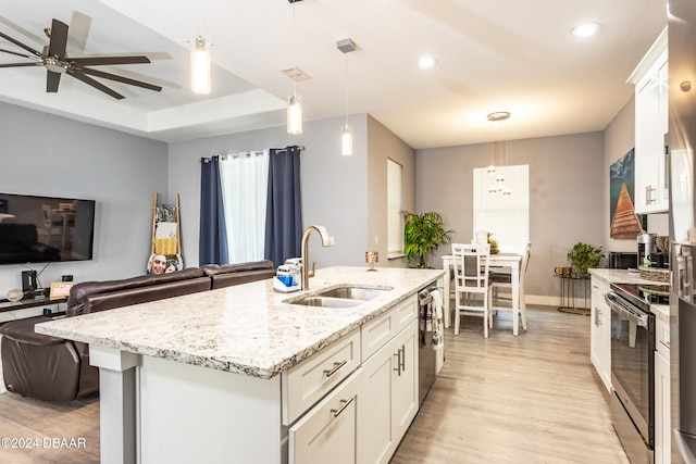 kitchen with light hardwood / wood-style floors, stainless steel appliances, a center island with sink, sink, and decorative light fixtures