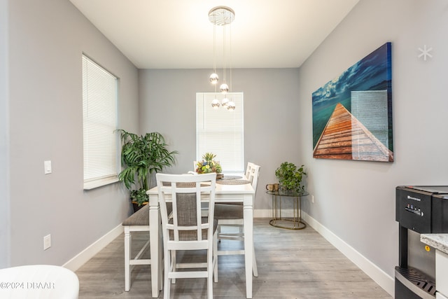 dining space featuring wood-type flooring, a healthy amount of sunlight, and a chandelier