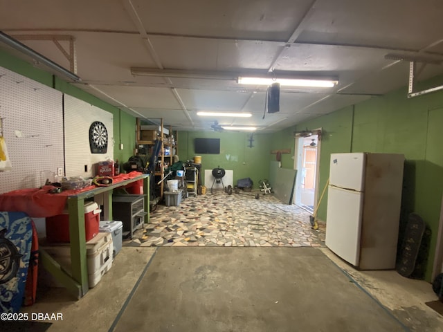 basement featuring white fridge and a workshop area