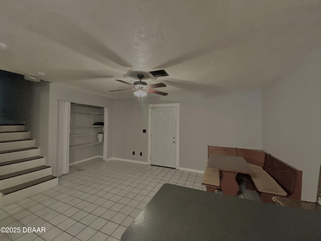 unfurnished living room with ceiling fan, a textured ceiling, and light tile patterned floors