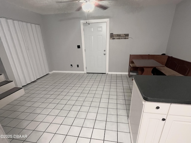 kitchen featuring ceiling fan, white cabinetry, a textured ceiling, and light tile patterned flooring