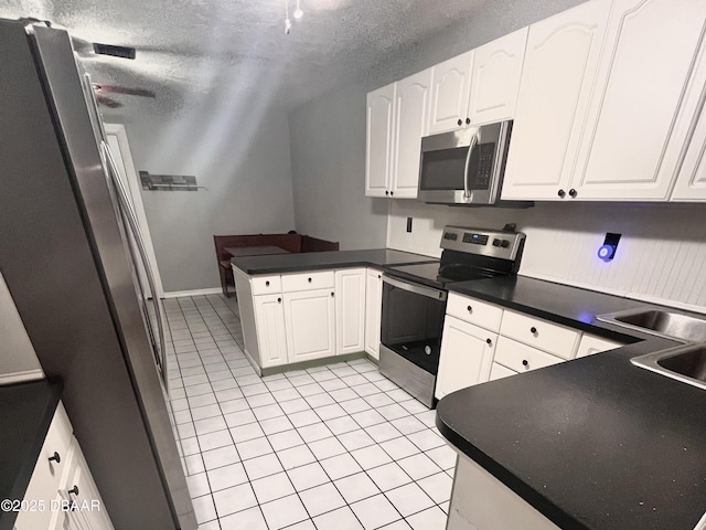 kitchen with white cabinetry, kitchen peninsula, stainless steel appliances, and light tile patterned flooring