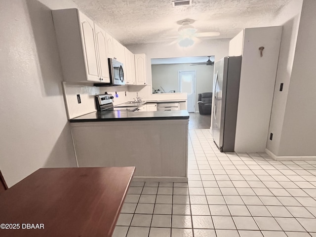 kitchen featuring kitchen peninsula, ceiling fan, white cabinets, a textured ceiling, and stainless steel appliances