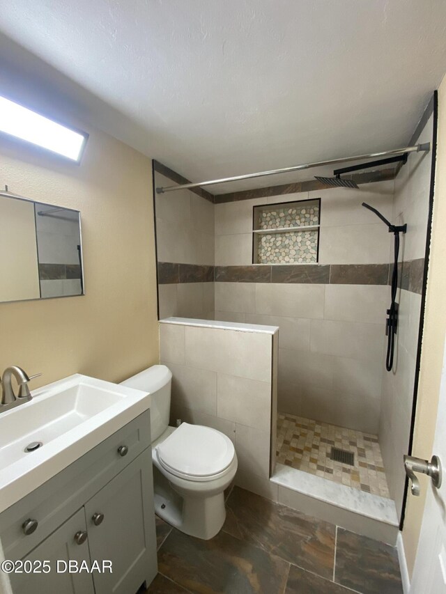 bathroom featuring toilet, walk in shower, and vanity