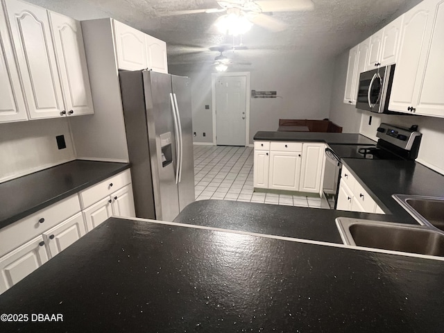 kitchen featuring ceiling fan, a textured ceiling, white cabinets, stainless steel appliances, and light tile patterned flooring