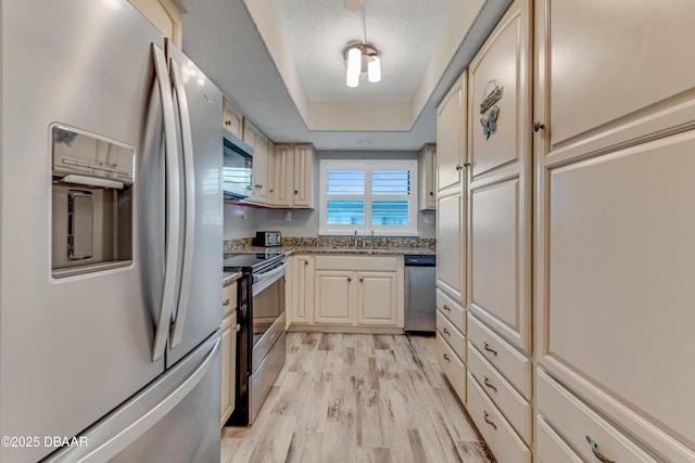 kitchen with sink, a textured ceiling, light hardwood / wood-style flooring, stainless steel appliances, and cream cabinets