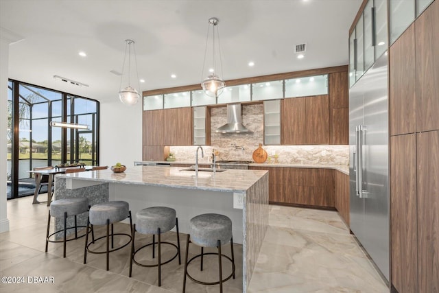 43 Del Palma Dr, Palm Coast, FL 32137 - kitchen with modern cabinets, wall chimney range hood, brown cabinetry, a sink, and a wall of windows