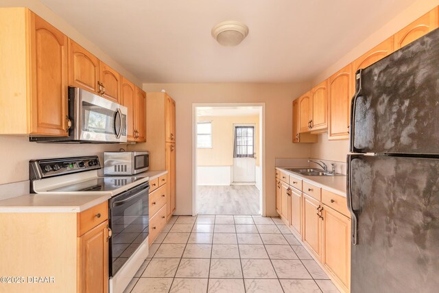 kitchen featuring black fridge, sink, white electric range, and light brown cabinetry