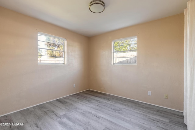 spare room featuring a healthy amount of sunlight and light hardwood / wood-style floors