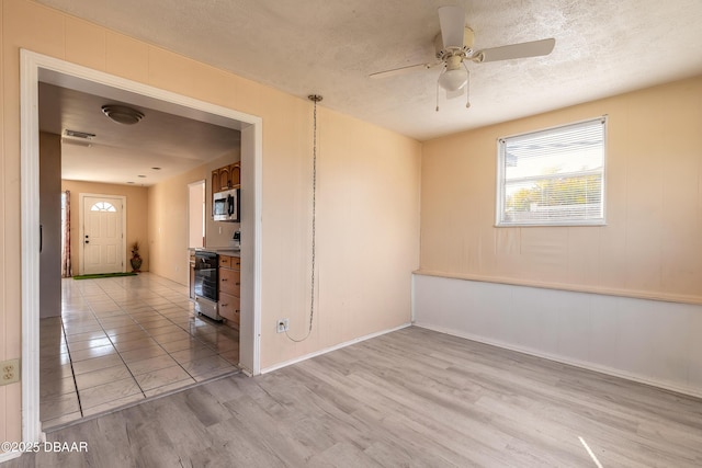 spare room with ceiling fan, light hardwood / wood-style flooring, and a textured ceiling