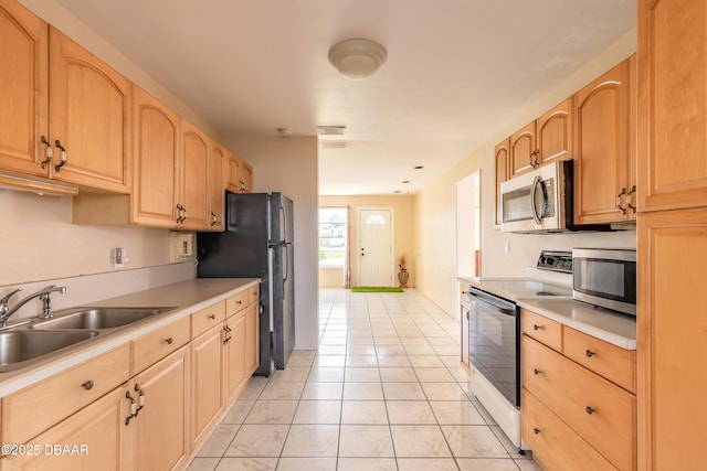 kitchen with appliances with stainless steel finishes, sink, light tile patterned floors, and light brown cabinetry