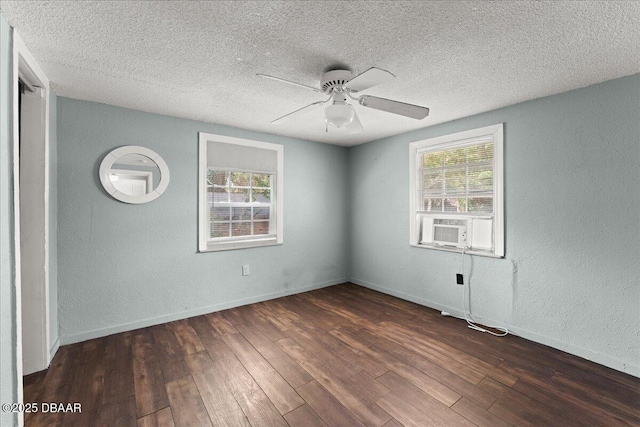empty room with wood finished floors, a textured ceiling, a textured wall, a ceiling fan, and baseboards