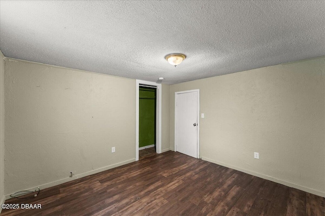 empty room with wood finished floors, a textured ceiling, and baseboards