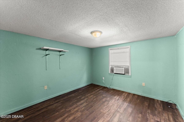 spare room featuring wood finished floors, cooling unit, baseboards, and a textured ceiling