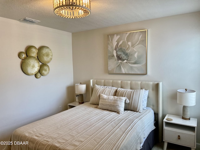 bedroom with visible vents and an inviting chandelier