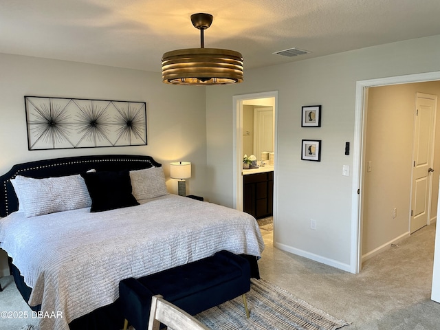 bedroom with visible vents, light carpet, ensuite bathroom, and baseboards