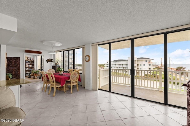 tiled dining area featuring a wall of windows and a textured ceiling