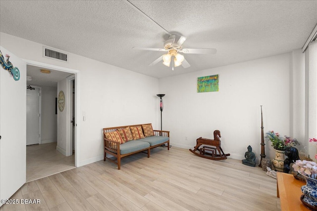 sitting room with ceiling fan, light hardwood / wood-style flooring, and a textured ceiling