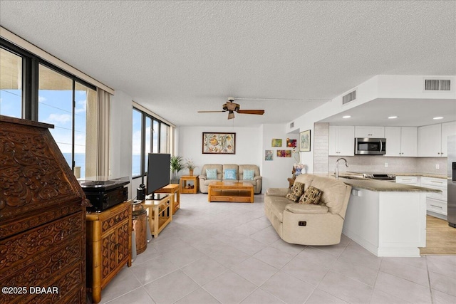 tiled living room with ceiling fan and a textured ceiling