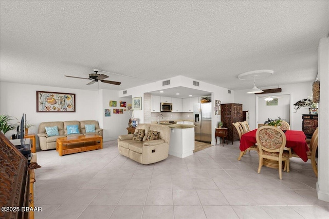 tiled living room featuring ceiling fan, sink, and a textured ceiling