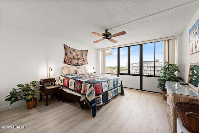 bedroom with ceiling fan, light hardwood / wood-style flooring, and a textured ceiling