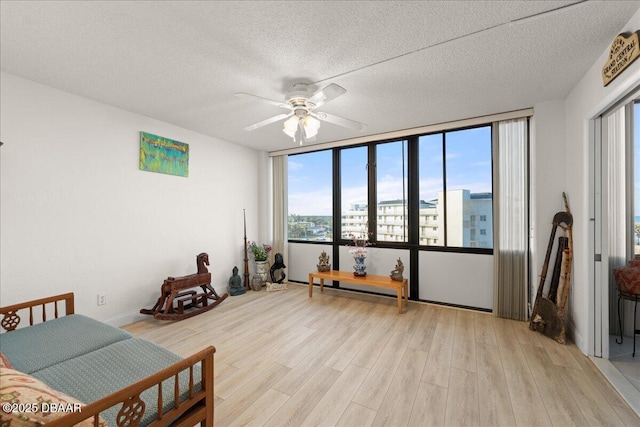 interior space featuring ceiling fan, light hardwood / wood-style floors, and a textured ceiling