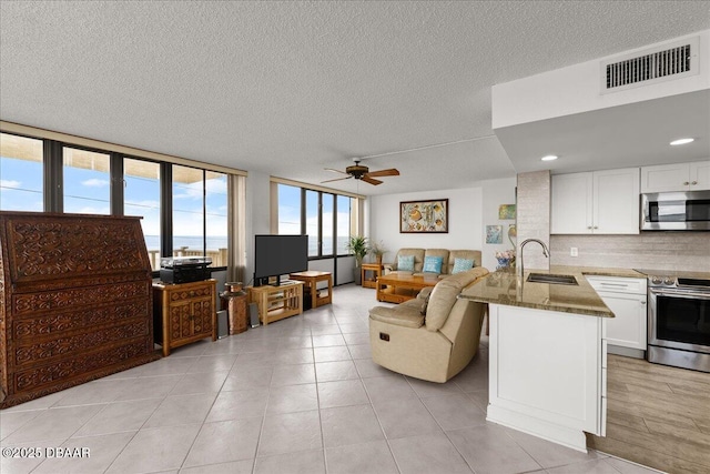 tiled living room with ceiling fan, sink, and a textured ceiling