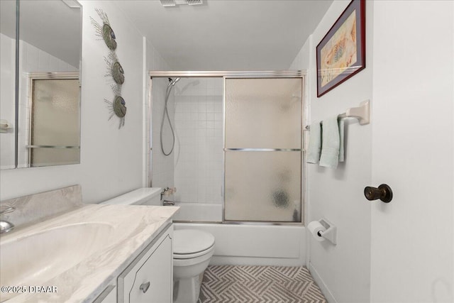 full bathroom featuring vanity, combined bath / shower with glass door, and toilet