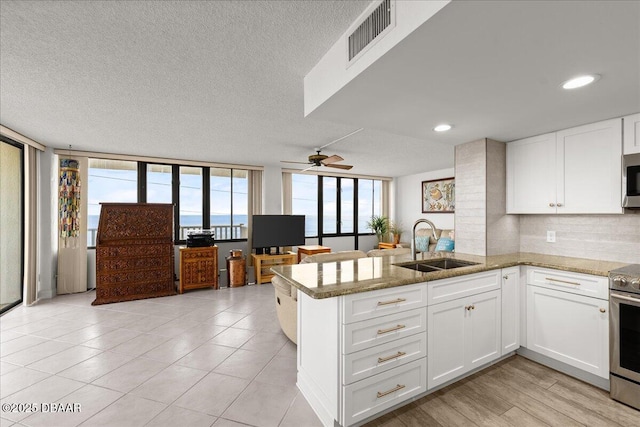 kitchen with white cabinetry, stainless steel appliances, kitchen peninsula, and sink