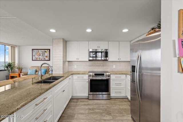 kitchen featuring light stone countertops, white cabinetry, appliances with stainless steel finishes, and sink