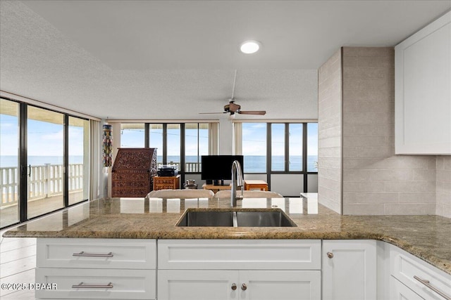 kitchen featuring stone counters, white cabinetry, sink, and kitchen peninsula