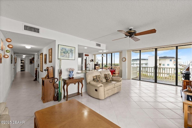 tiled living room featuring floor to ceiling windows, a wealth of natural light, a textured ceiling, and ceiling fan