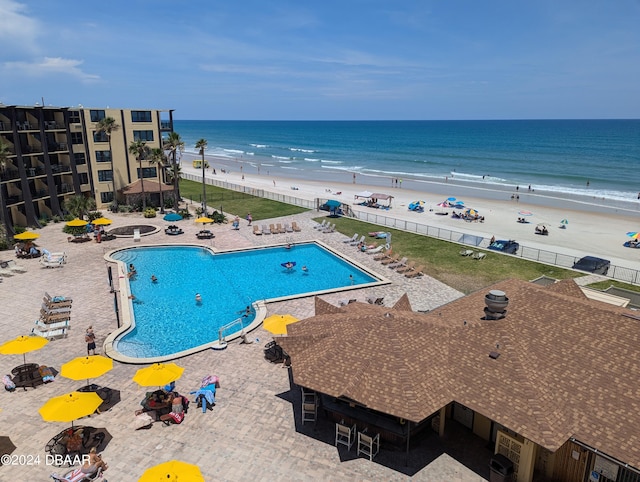 view of swimming pool featuring a patio area, a view of the beach, and a water view