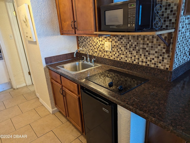 kitchen with black appliances, light tile patterned flooring, backsplash, sink, and dark stone countertops